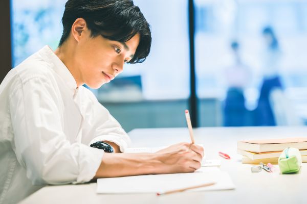 ノートに書き込む手、レビュー会議のイメージ。