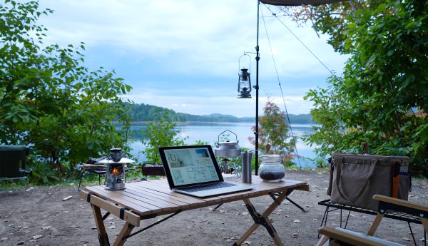 ボーイスカウトの敬礼ポーズ+背景に青空とキャンプ。または、キャンプと仕事を融合したイメージ